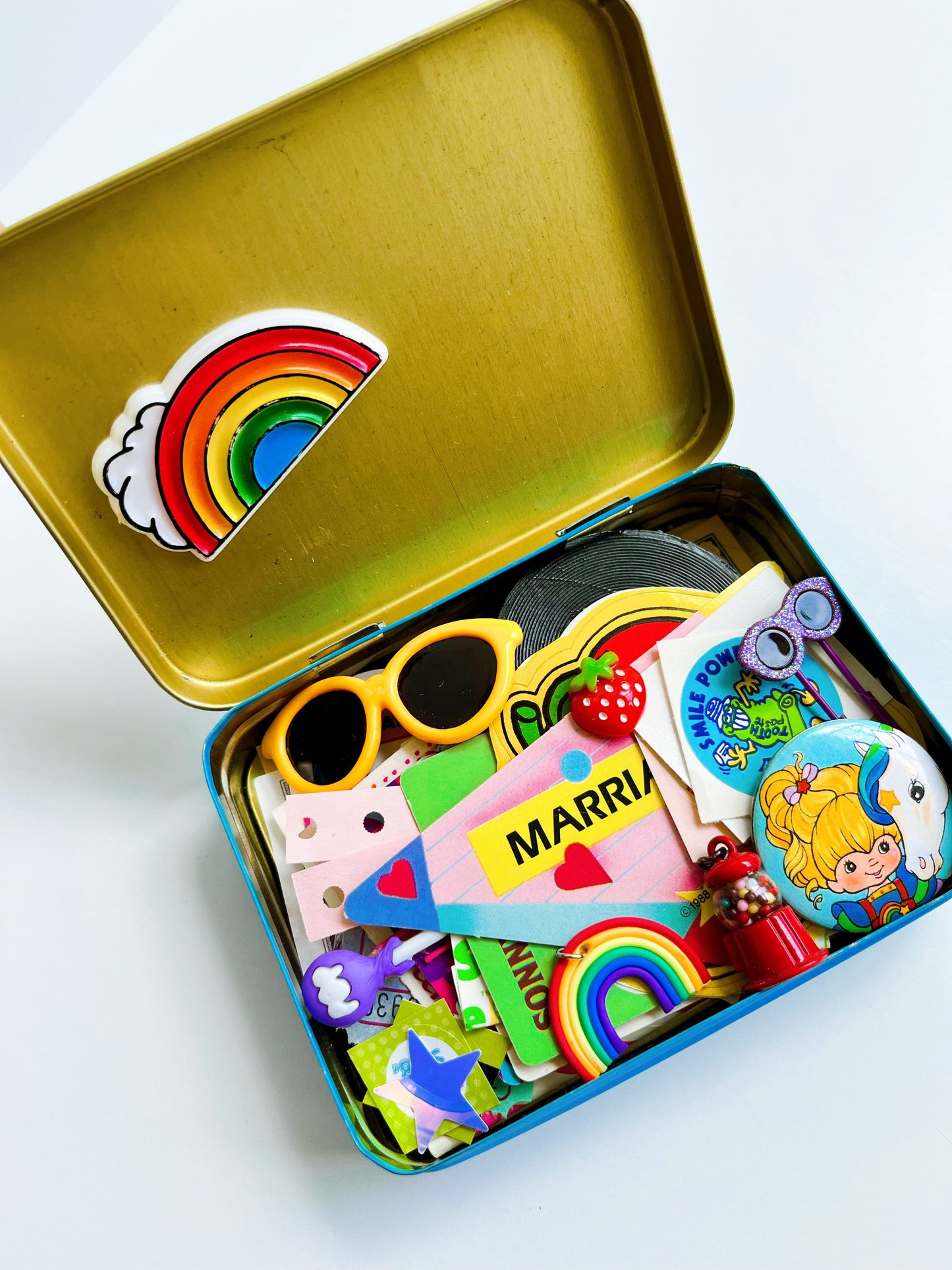 Vintage rainbow tin filled with 80’s themed ephemera & pieces